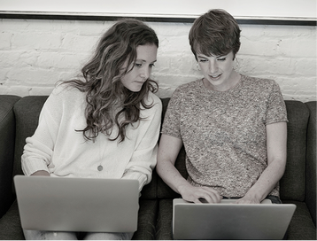 women and men siting of sofa with their laptops and chatting over monitor on the mens laptop